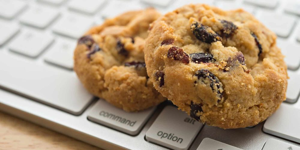 Two chocolate chip cookies on a computer keyboard